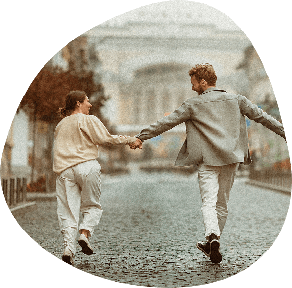 Photo d'un jeune couple marchant en se tenant la main, vue de dos dans une rue